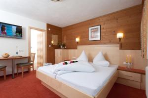 a bedroom with a large white bed and a desk at Hotel Garni DIAS - Silvretta Card Premium inklusive in Kappl