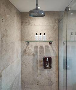 a bathroom with a shower with three bottles of soap at Keepers Cottage Guest House in Holt