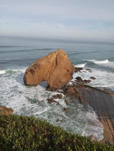 a large rock in the ocean next to a beach at LS Beach House in A dos Cunhados