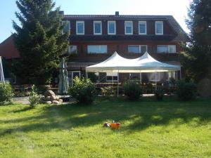 une maison avec une tente dans l'herbe en face de celle-ci dans l'établissement Landgasthof Allerparadies, à Langlingen