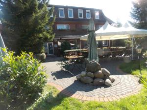 eine Terrasse mit einem Sonnenschirm, einem Tisch und Stühlen in der Unterkunft Landgasthof Allerparadies in Langlingen