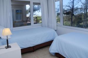 a bedroom with two beds and two windows at Jaina Resort & Spa in Mar de las Pampas