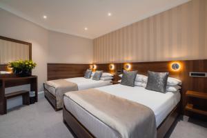a hotel room with two beds and a desk at London House Hotel in London