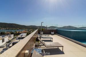 a balcony with benches and a view of the water at Estadia com piscina e sauna a poucos passos da praia em Cabo Frio - HSC in Škorak