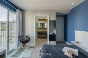 a bedroom with blue walls and a bed and a chair at Estadia com piscina e sauna a poucos passos da praia em Cabo Frio - HSC in Škorak +16 photos