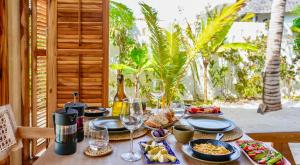 a table with plates of food and wine on it at MAKU Oasis Villas and Studios in Makunduchi