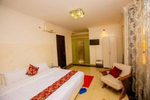 a bedroom with a large white bed and a chair at INFINITY Hotel in Kigali