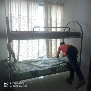 a man is making a bed in a room at The Valley, SkySierra KL in Kuala Lumpur