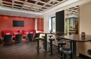 a bar with two tables and red chairs at Leonardo Hotel Mönchengladbach in Mönchengladbach