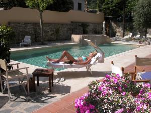 a woman laying in a hammock by a swimming pool at Hotel Torretta in Montecatini Terme