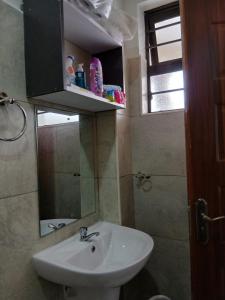 a bathroom with a sink and a mirror at A cozy spacious studio apartment with a balcony in Nairobi