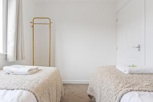 a white room with two beds with towels on them at The Cosy House with Free Parking, Garden and Smart TV with Netflix by Yoko Property - Perfect for Contractors, Groups & Relocation in Leamington Spa +17 photos