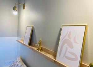 a shelf with two pictures and a lamp on a wall at La Perle Marine in Fleury +4 photos