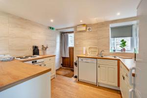 a kitchen with white cabinets and a sink and a window at Magpie Cottage in Newton