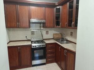 a kitchen with wooden cabinets and a stove and a sink at Benefice Apart in Yerevan