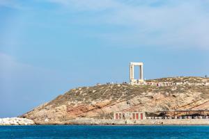 a lighthouse on top of a hill next to the water at Kavuras Village Hotel & Suites in Agios Prokopios