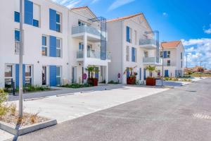 a row of white apartment buildings with blue windows at Suite Olonna Spa et Terrasse à 7 min des plages in Les Sables-dʼOlonne