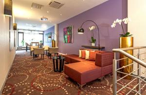 Un vestíbulo con un sofá, una mesa y sillas. en Leonardo Hotel Munich City North, en Múnich