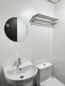 a white bathroom with a sink and a mirror at Covent Garden Condominium in Manila