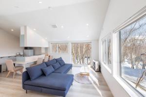a living room with a blue couch and a kitchen at 豆の家Beanz House in Niseko