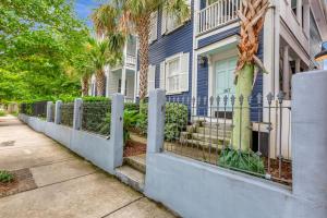 チャールストンにあるRetreat on Spring, Unit Aのヤシの木が生えている青い家の前の柵