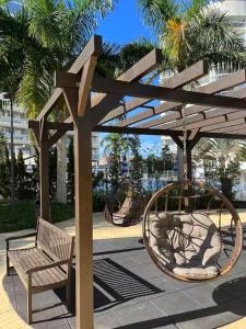 a bench and a swing set in a park at Nautilus Apto Beiramar Churrasqueira Piscina Beto Carrero in Penha