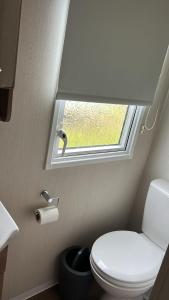 a bathroom with a toilet and a window at Heysham Coastal Escape Family 3-Bed Caravan in Heysham +9 photos