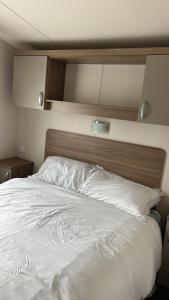 a large white bed with a wooden head board at Heysham Coastal Escape Family 3-Bed Caravan in Heysham