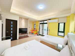 two beds in a room with a television and a living room at 幸福滿屋民宿-包棟詢問 in Hualien City