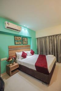 a bedroom with a large bed with red pillows at Hotel Akasa International Near T-2 International Airport Mumbai in Mumbai