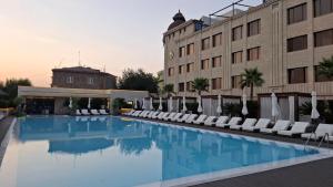 a hotel swimming pool with white chairs and a building at Venice Hotel Complex in Yerevan
