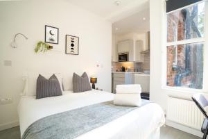 a white bedroom with a bed and a window at Central Harrow 5 Studio Apartment Block in Harrow