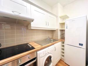 a kitchen with white cabinets and a washer and dryer at One Bedroom Site Apartment in Dublin +4 photos
