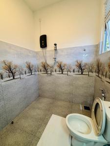 a bathroom with a toilet and trees on the wall at Revival Beach Resort in Hikkaduwa