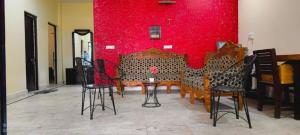 una stanza con sedie e una parete rossa di Voyageurs Homestay ad Agra