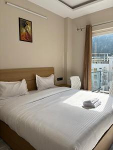 a bedroom with a large white bed with a window at Hotel Abline the Oaks in Rishīkesh +100 photos