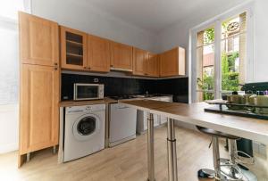 a kitchen with wooden cabinets and a washer and dryer at Appartement André Thérèse, calme Belle Epoque in Vichy