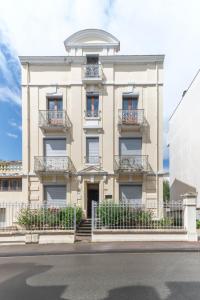 a large white building with balconies on a street at Appartement André Thérèse, calme Belle Epoque in Vichy