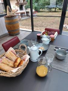 a table with a basket of bread and a basket of orange juice at Le petit nid dans les bois in Castres-Gironde