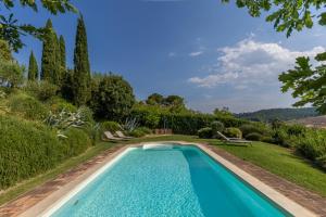 an infinity pool in a garden with trees and bushes at Il Colle Verde in Buonconvento