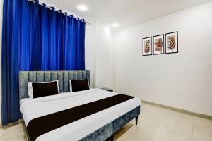 a bedroom with a large bed with blue curtains at Hotel O A-1 Stays in Faridabad