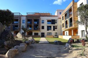 an apartment building with rocks in front of it at Stéphi - Superbe T2 accès plage, piscine chauffée in Pianottoli-Caldarello