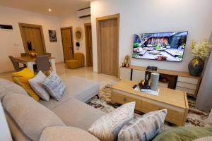 a living room with a couch and a flat screen tv at Stylish Apartment with Modern Amenities in Nova Roman Ridge in Accra