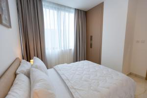 a white bed in a room with a window at Stylish Apartment with Modern Amenities in Nova Roman Ridge in Accra +38 photos