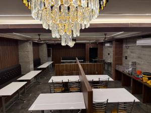 a dining room with tables and chairs and a chandelier at AJF Beach Inn in kāraikāl