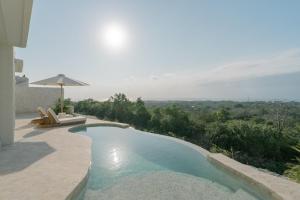 a swimming pool with a chair and an umbrella at Nour Uluwatu in Uluwatu