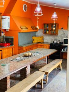 a kitchen with orange walls and a table and benches at Nuestro sueño in San Carlos de Bolívar