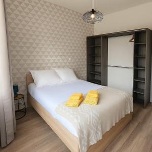 a bedroom with a bed with two yellow towels on it at Elégant T2 au calme avec terrasse et climatisation in Angoulême