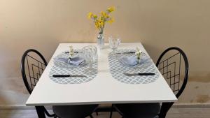 a white table with two chairs and a vase with flowers at Casa Mobiliada com 4 camas e 2 quartos in Juazeiro do Norte