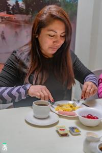 eine Frau, die mit einem Teller Essen an einem Tisch sitzt in der Unterkunft GS Hoteles-Cajamarca in Cajamarca